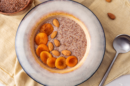 Flax vegan porridge from fresh seeds with almonds and dried apricots on a light background. Source Omega 3.の写真素材
