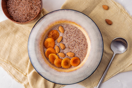 Flax vegan porridge from fresh seeds with almonds and dried apricots on a light background. Source Omega 3.の写真素材