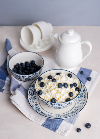 Cottage cheese with blueberries in a porcelain plate on a white background.の写真素材