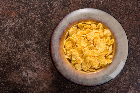 Cornflakes in a ceramic plate on a dark background. Breakfast.