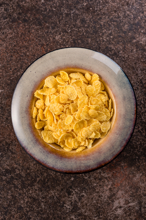 Cornflakes in a ceramic plate on a dark background. Breakfast.の写真素材
