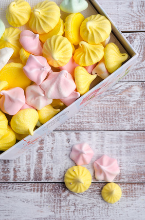Multi-colored meringue in a gift box on wooden vintage background.の写真素材