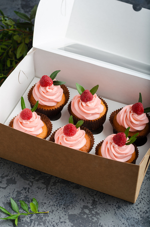 Cupcakes with raspberry cream, decorated with raspberries on top on gift wrap.の写真素材