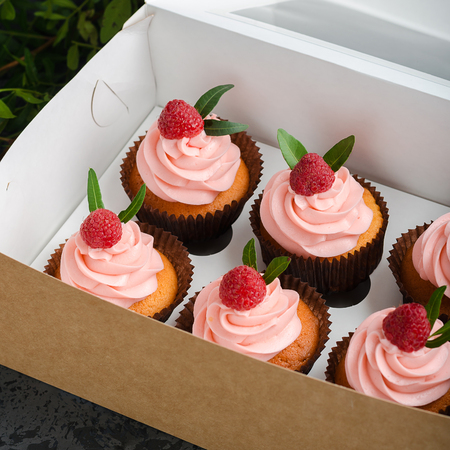 Cupcakes with raspberry cream, decorated with raspberries on top on gift wrap.の写真素材