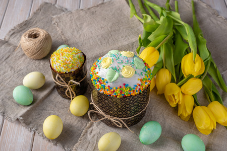 Easter still life. Easter cake, painted eggs with tulips on a wooden old rustic background.