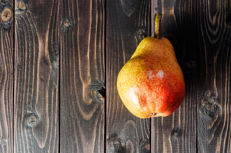 Bright red-yellow pears in a basket on a dark wooden rustic background. Autumn harvest of fruits.の写真素材
