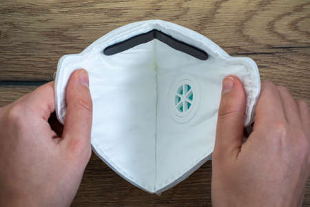 Woman hands holding a medical face dust filter mask, disposable FFP2 FFP3 respirator. Concept of...