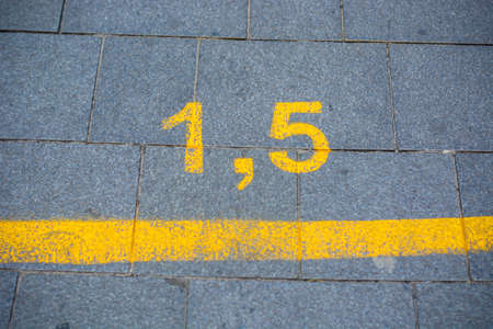 Yellow marking on the street in order to guide social distancing due to the coronavirus or covid-19 pandemic. Yellow marking indicating how much distance people should keep to be safe.の写真素材