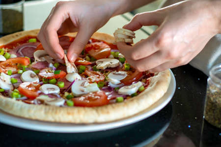 Homemade pizza with vegetables. The process of making pizza at home. Hands of woman making pizza and...