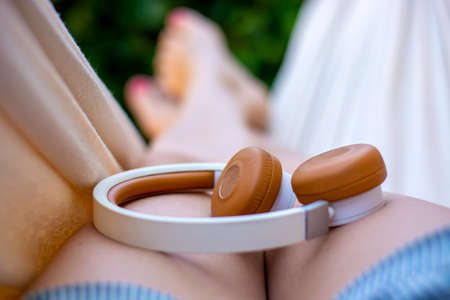 Female legs with headphones in a hammock. A woman with bare feet relaxing and enjoying a lovely...