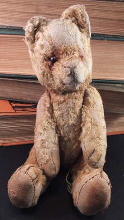 single old teddy bear sat in front of old booksの写真素材