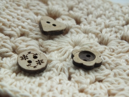 Three shaped wooden vintage buttons on cream vintage crochet