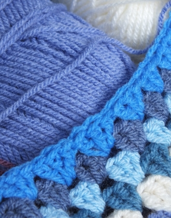 Blue yarn with a section of blue crochet afghan blanketの写真素材