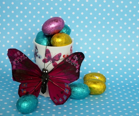 Small foil wrapped easter eggs in a butterfly decorated egg cup with a pink butterflyの写真素材