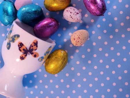 Mini easter eggs spilling out of a butterfly decorated egg cupの写真素材