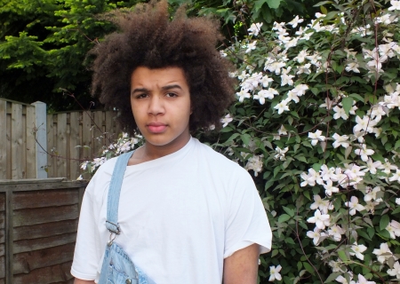 Teenage mixed race  boy wearing dungarees in the gardenの写真素材