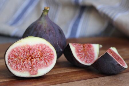 Whole and cut figs on wooden board in kitchen
