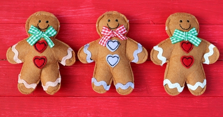 Three felt ginger bread men on red painted festive.の写真素材