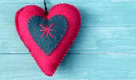 Traditional felt heart decoration in pink and blue, with blanket stitch on blue wooden background の写真素材
