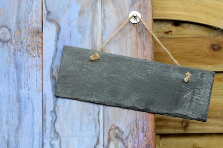Rectangle blank slate shabby chic sign hanging on a blue weathered a painted shed dooの写真素材