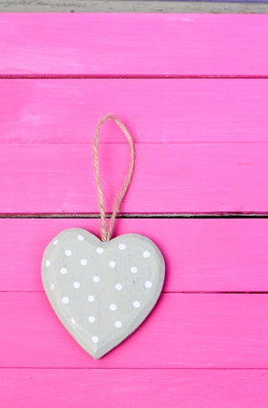 Pale olive spotted shabby chic heart on a bright pink painted wooden floorboardsの写真素材