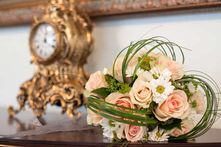 Close-up of roses and daisies flowers in elegant bouquet with green elements lying on tableの写真素材