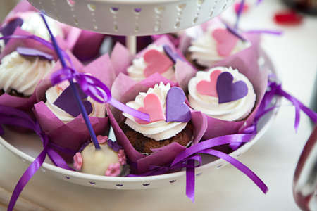 White plate with chocolate cakes with white cream, pink and purple decoration hearts in Moscow restaurantの写真素材