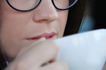 Photo of the Young woman drinking coffee in a cafe outdoorsの写真素材