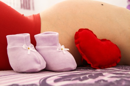 Photo of the Pregnant woman with baby shoesの写真素材