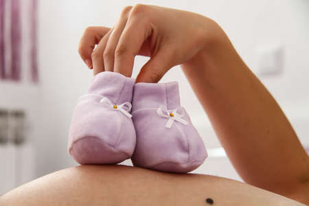 Photo of the Pregnant woman with baby shoesの写真素材