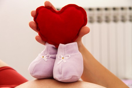 Photo of the Pregnant woman with baby shoesの写真素材
