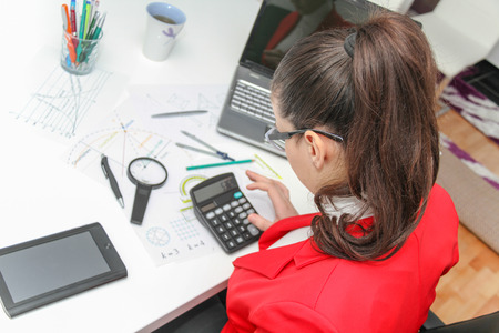 Photo of the Young female designer working with architectural plan in her modern home officeの写真素材