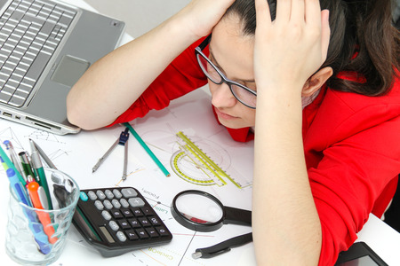 Photo of the Young female designer working with architectural plan in her modern home officeの写真素材