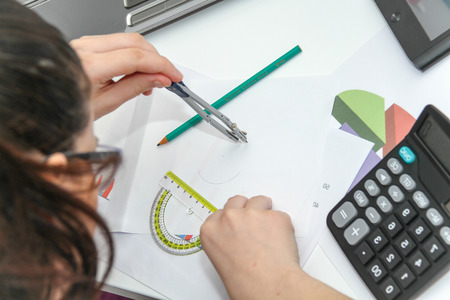 Photo of the Pretty Business woman analyzing investment charts with calculator and laptopの写真素材