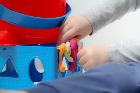 Little boy three years old sits on the table and plays with plasticine and wooden and plastic toys, cubes and diceの写真素材