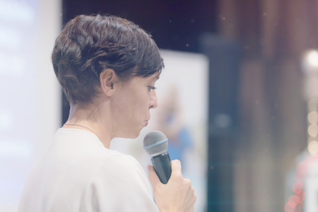 Beautiful business woman with microphone in her hand speaking at the  conference or seminar.の写真素材