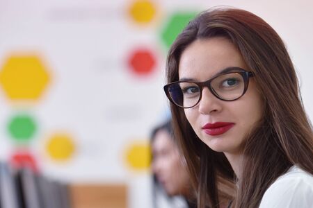Beautiful female student wearing glasses working at computer lab at university campus interior....