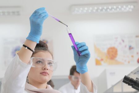 Two Young Female and male Laboratory scientists working at lab with test tubes and microscope, test...