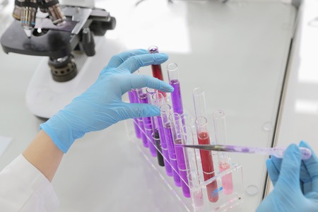 Young female Laboratory scientist working at lab with test tubes and microscope, test or research in...