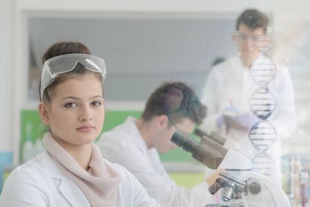 Group of young Laboratory scientists working at lab with test tubes and microscope, test or research...