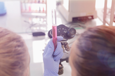 Two young Laboratory scientists working at lab with test tubes and microscope, test or research in clinical laboratory. Science, chemistry, biology, medicine and people concept.の写真素材