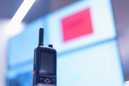 Security guard monitoring modern CCTV cameras in surveillance room. Portable radio at the table.