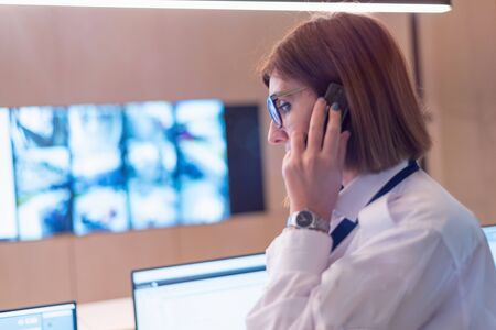 Security guard monitoring modern CCTV cameras in surveillance room. Female security guard in...