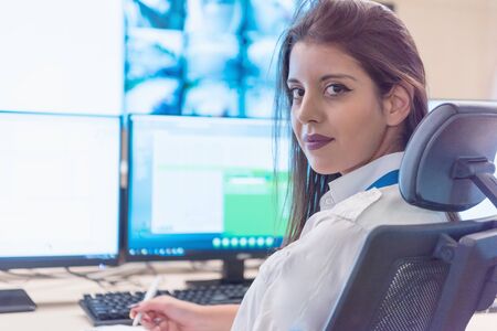 Security guard monitoring modern CCTV cameras in surveillance room. Female security guard in...