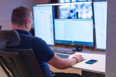 Security guard monitoring modern CCTV cameras in surveillance room.  Male security guard in...
