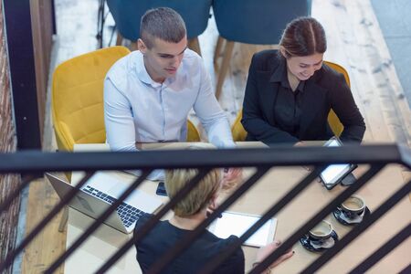 Multiracial business people working connected with technological devices at the bar. Group of three...