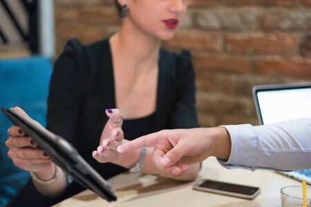 Multiracial business people working connected with technological devices at the bar. Group of three young creative coworkers working with new startup project.の写真素材