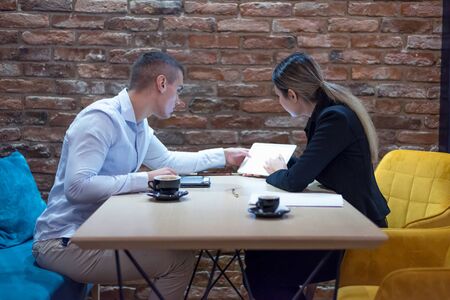 Two young business people brainstorming and discussing business plan on meeting at sunny bright...
