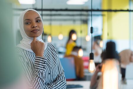 Young muslim African American business woman as a leader at work. Teamwork and multiethnic concept. Happy successful business leader working at her office, looking and smiling into camera.の写真素材