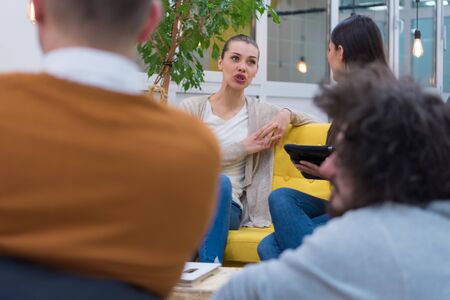 Group of a young business multiethnic people brainstorming and discussing business plan on meeting at sunny bright office interior.の写真素材